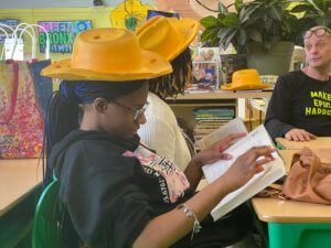 One of our Local Leaders students wearing a cheese hat and reading a copy of Mr. Ritz book: "The Power of a Plant.