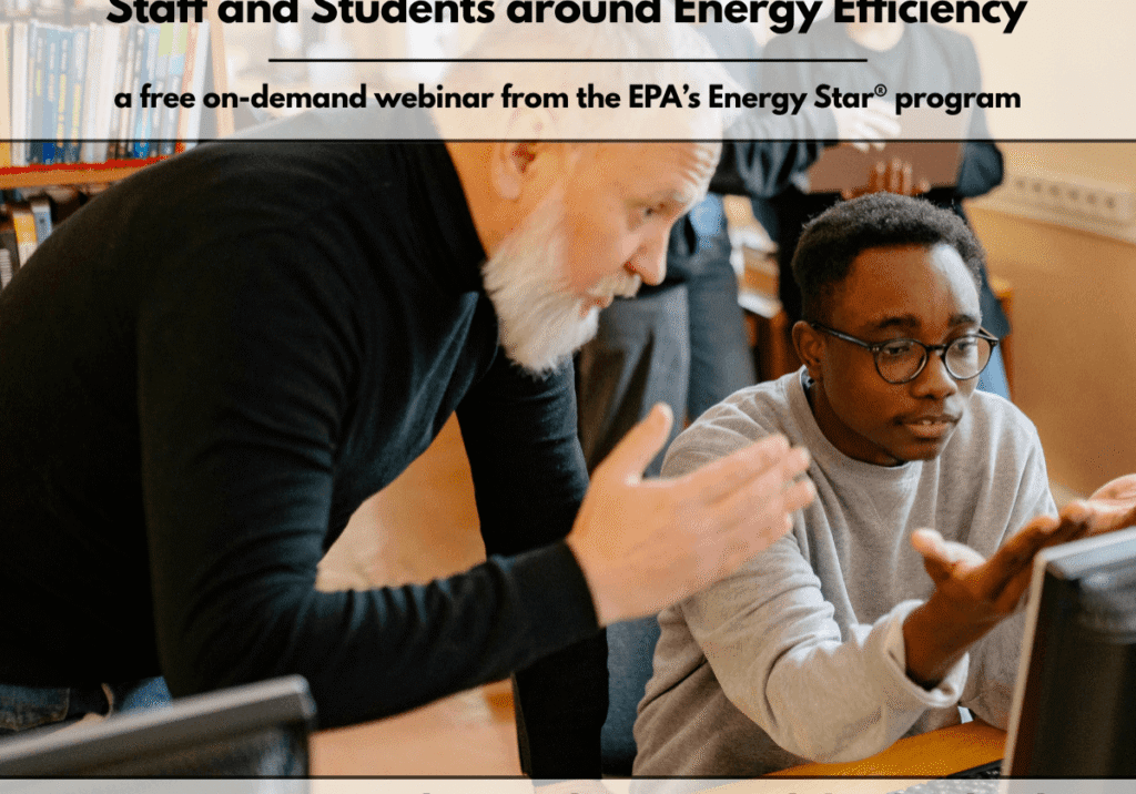 An adult mentor and teenage student examine energy data together on a desktop computer in a school library.